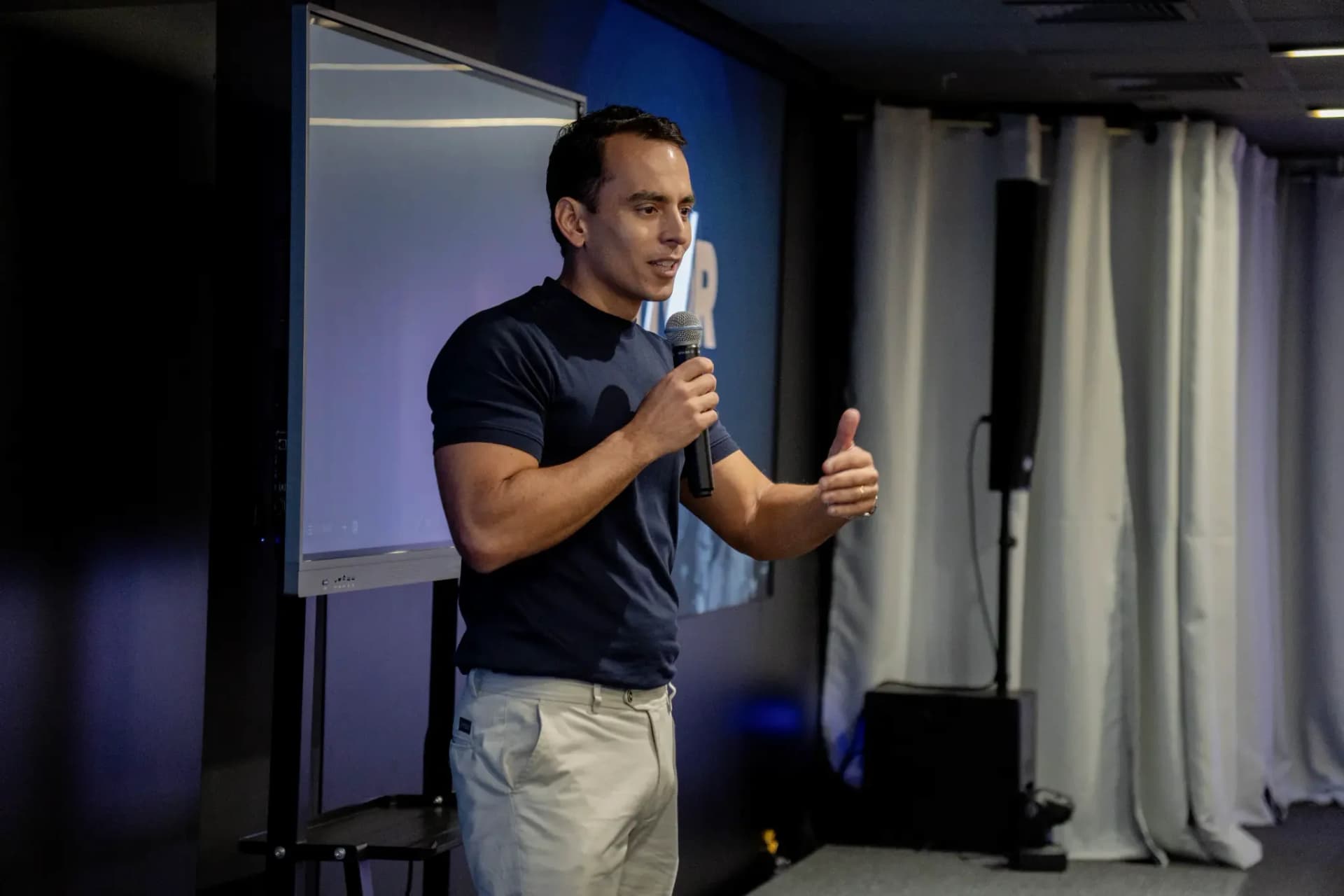 Vitor Novaes falando ao microfone durante uma palestra